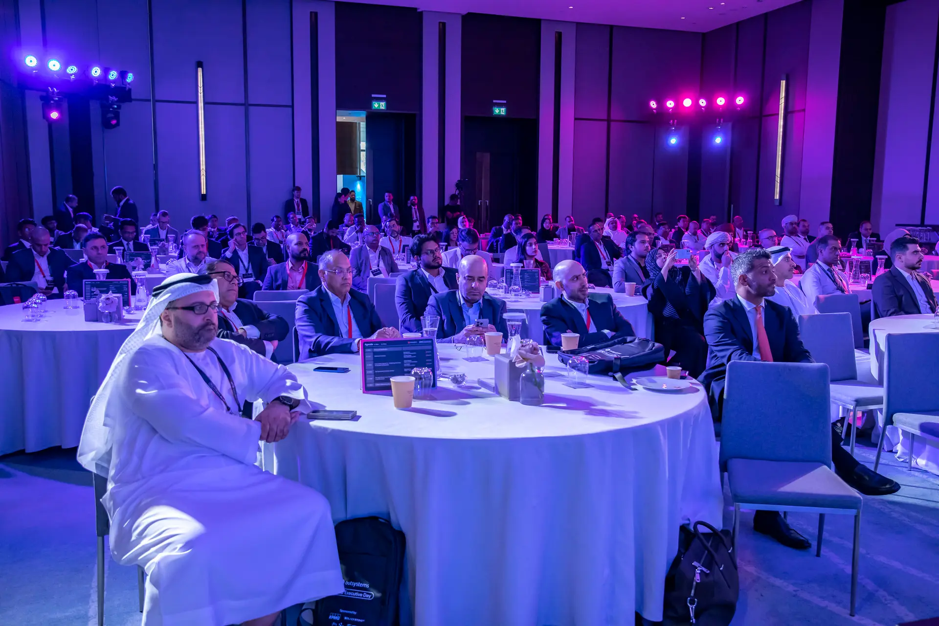 Delegates seated at round tables in the main room